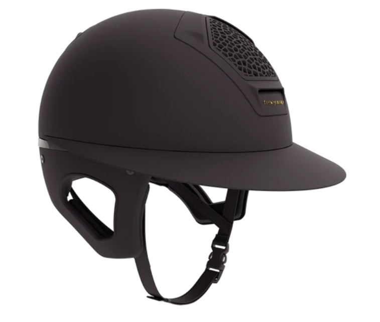A matte black equestrian riding helmet with a visor, featuring a honeycomb-patterned ventilation grille on the top and a small gold logo on the front shown against a plain white background.